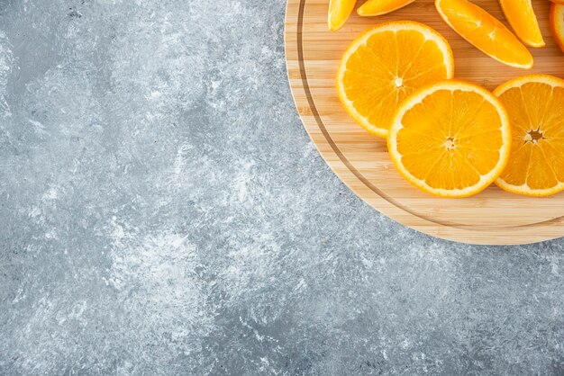 Una tavola di legno piena di succose fette di frutta arancione sul tavolo di pietra.