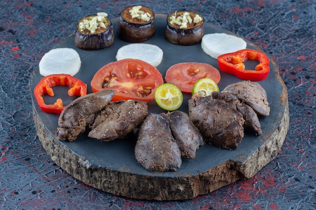 Una tavola di legno scuro di verdure e carne.