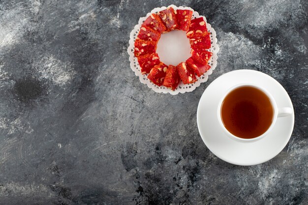 Una tazza bianca di tè caldo con il dessert affettato.