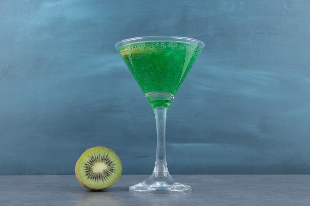 Una tazza di bicchiere da cocktail di succo di kiwi con una fetta di frutta.