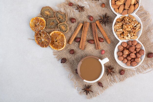 Una tazza di caffè con arance essiccate e noci su fondo marmo. Foto di alta qualità