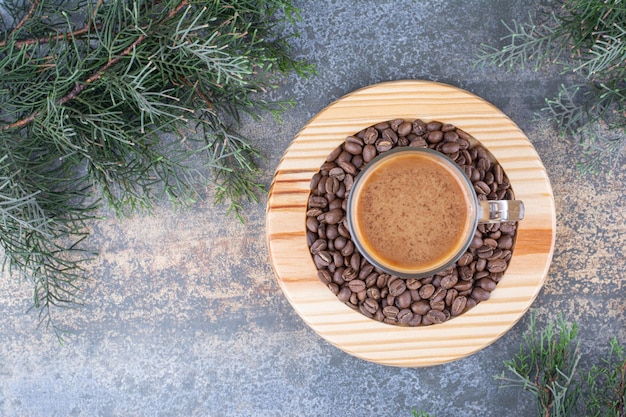 Una tazza di caffè con chicchi di caffè sulla tavola di legno.