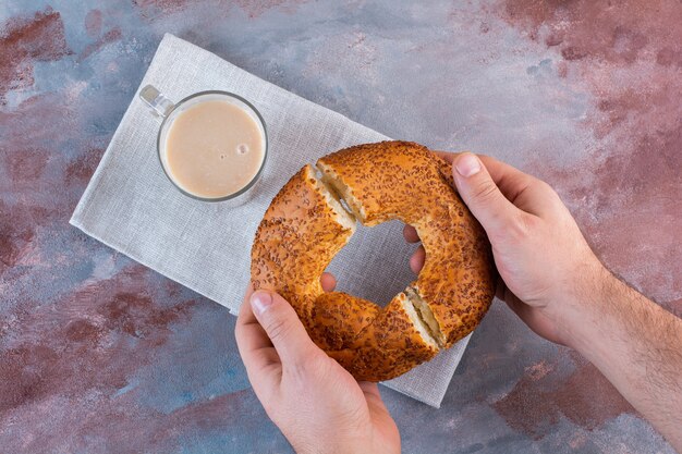 Una tazza di caffè con latte e bagel turco a fette sulla superficie di marmo