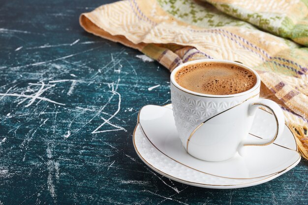 Una tazza di caffè con schiuma in un piattino bianco.