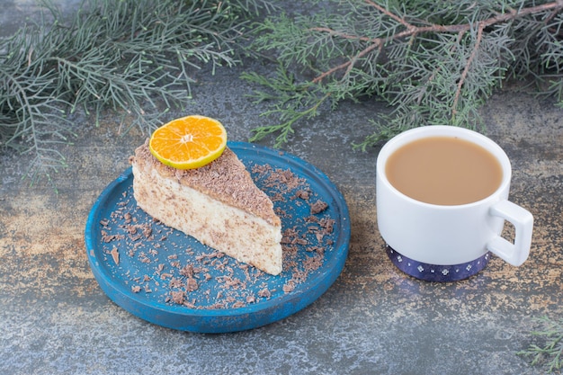 Una tazza di caffè con un pezzo di torta gustosa sul piatto blu. Foto di alta qualità