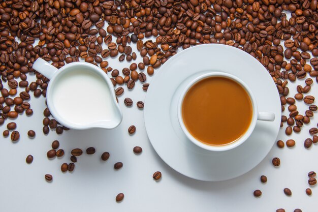 Una tazza di caffè con vista dall'alto di latte con chicchi di caffè sulla superficie