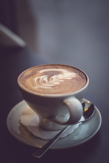 Una tazza di caffè e un cucchiaio bianchi su un tavolo.