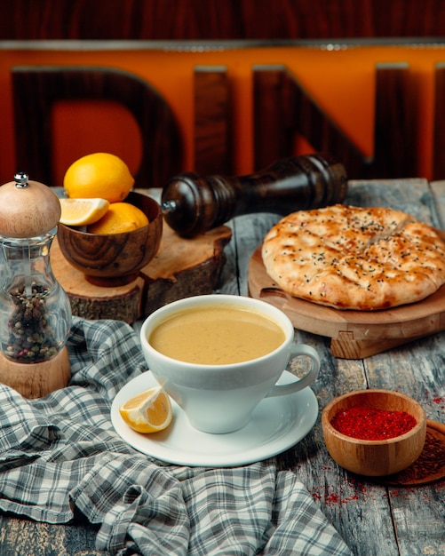 Una tazza di caffè latteo con fette di limone e torta di pasta intorno.