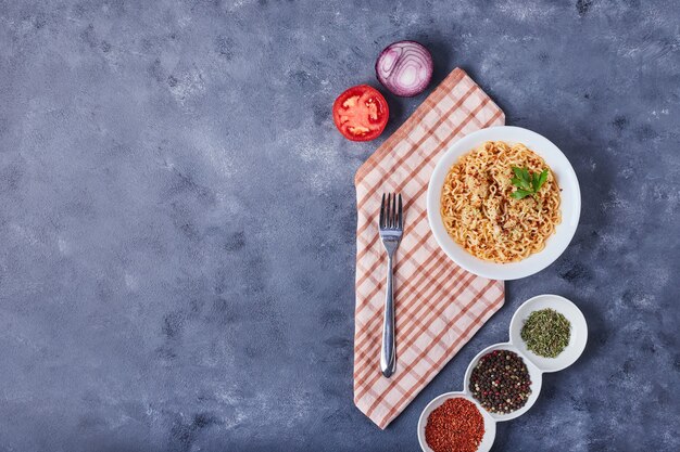 Una tazza di spaghetti con spezie e verdure.