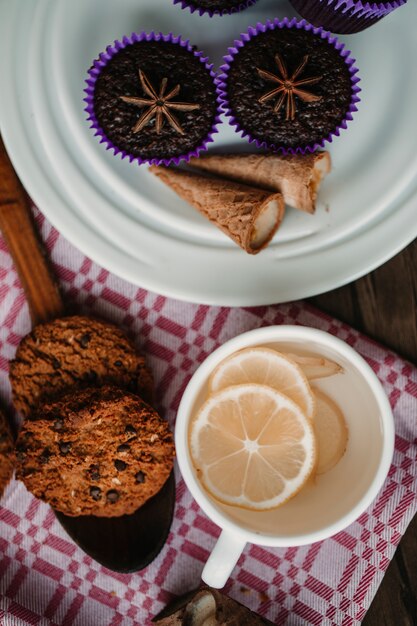 Una tazza di tè allo zenzero e limone con biscotti e brownie.