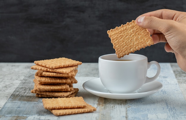 Una tazza di tè aromatico con cracker su un tavolo di legno.