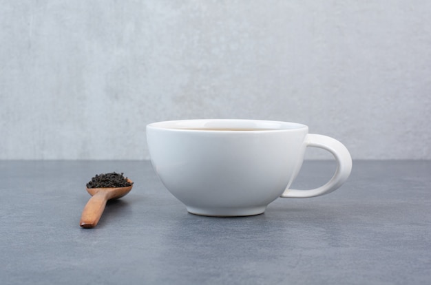 Una tazza di tè aromatico con un cucchiaio di legno di infuso.
