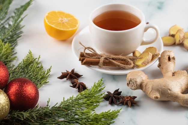 Una tazza di tè con cannella, limone e zenzero su un tavolo di marmo decorato di Natale.
