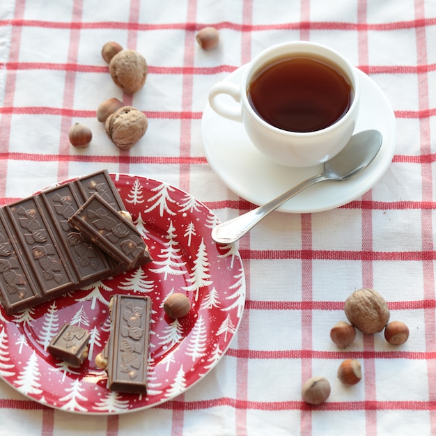 Una tazza di tè con una barretta di cioccolato sull'asciugamano a quadri.