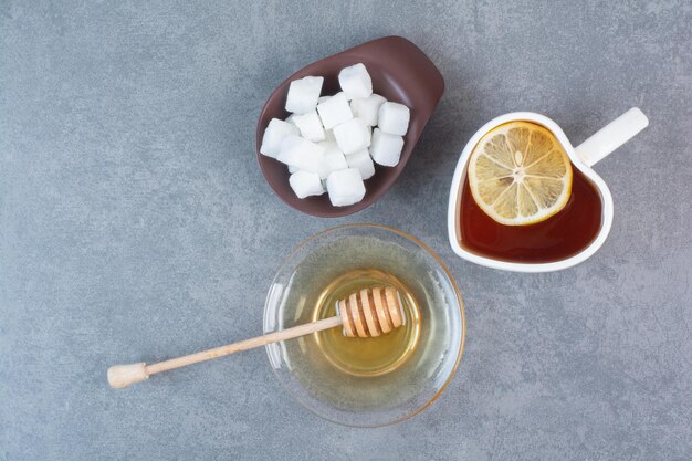 Una tazza di tè con zucchero e miele sulla superficie grigia