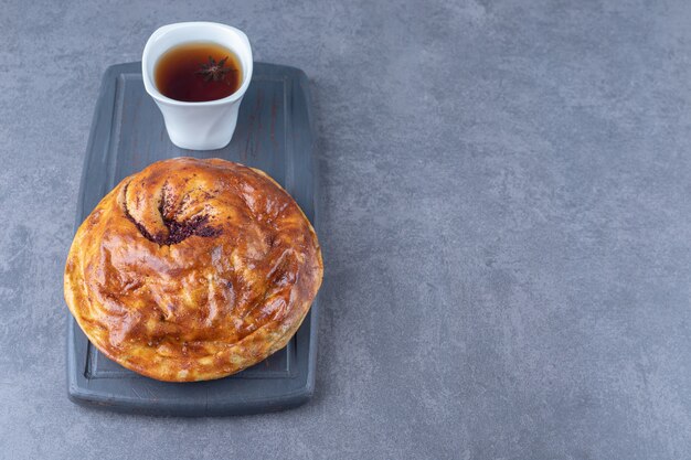 Una tazza di tè e torta dolce su un vassoio di legno sul tavolo di marmo.