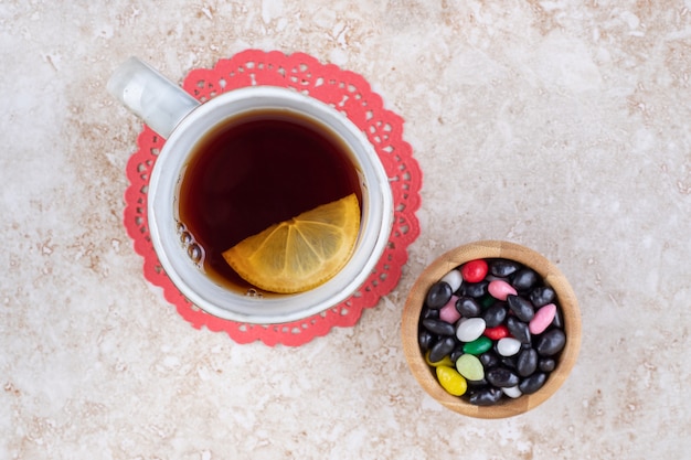 Una tazza di tè su un centrino e una porzione di caramelle assortite