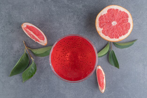 Una tazza di vetro con succo rosso e fette di pompelmo