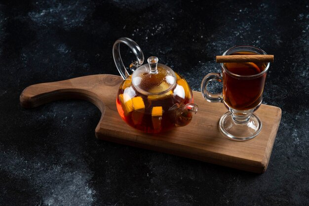 Una tazza di vetro con tè caldo e bastoncini di cannella.