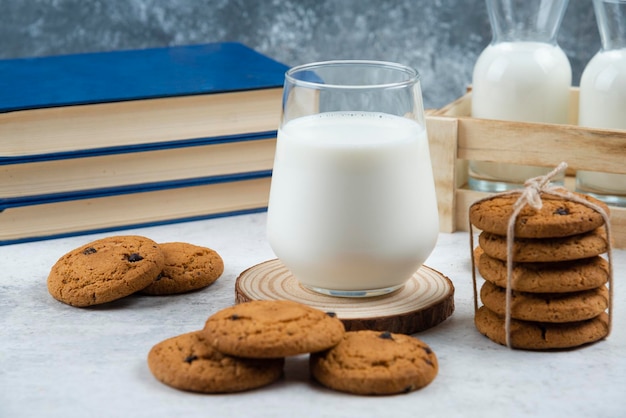 Una tazza di vetro di gustoso latte con biscotti e libri.