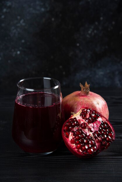 Una tazza di vetro di succo con melograno su oscurità.