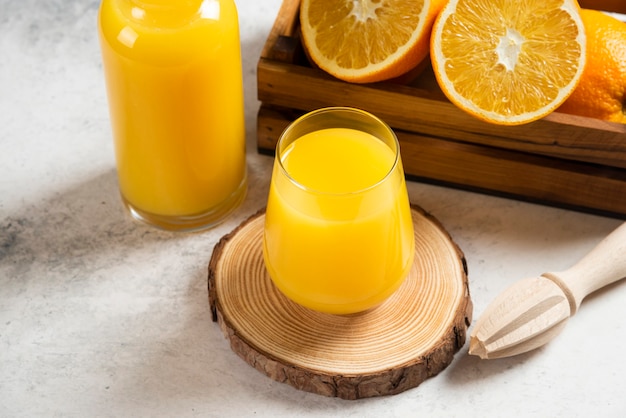 Una tazza di vetro di succo d'arancia fresco su tavola di legno.