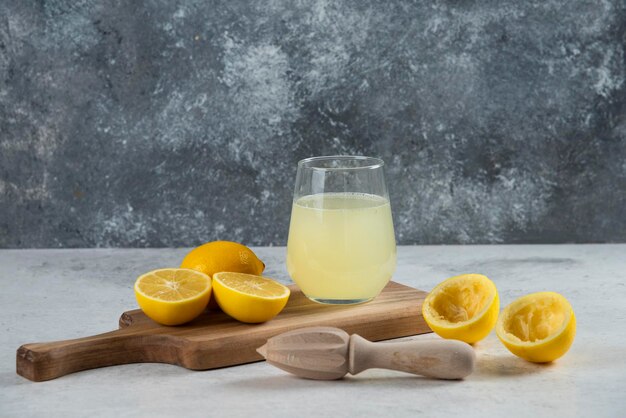 Una tazza di vetro di succo di limone fresco su una tavola di legno.