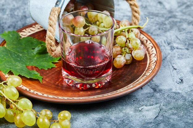 Una tazza di vino con grappoli d'uva intorno.