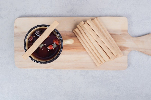 Una tazza gialla con bastoncini dolci sulla tavola di legno. Foto di alta qualità