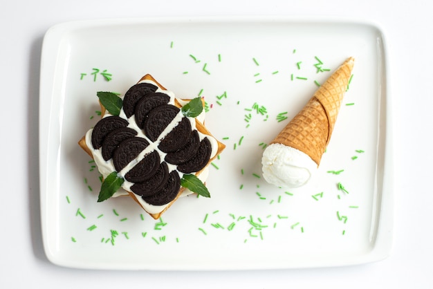 Una torta a base di biscotti al cioccolato con vista dall'alto e crema pasticcera insieme al gelato all'interno della foto del biscotto di zucchero dolce della scrivania bianca