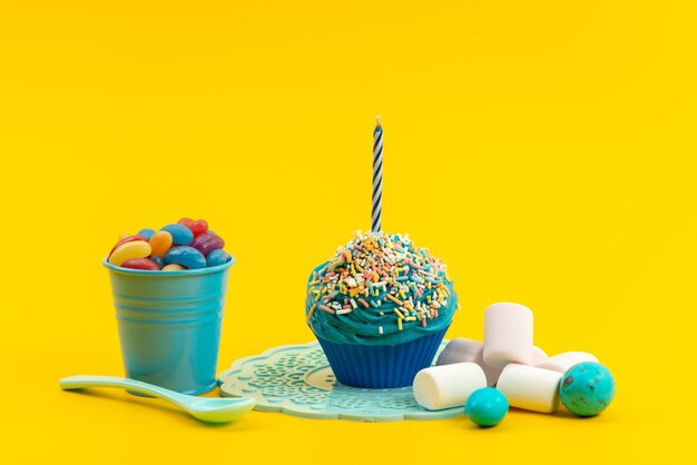 Una torta blu vista frontale con candela insieme a marmellate colorate e marshmallow su colore giallo, zucchero dolce biscotto