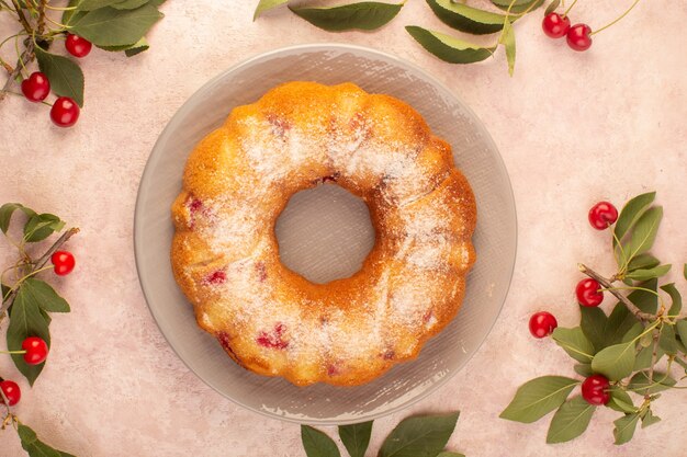 Una torta di ciliegie con vista dall'alto si è formata all'interno della lastra grigia sullo zucchero rosa del biscotto della torta dello scrittorio