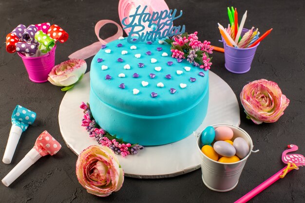 Una torta di compleanno blu con vista dall'alto con caramelle e decorazioni colorate tutt'intorno