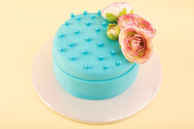 Una torta di compleanno blu di vista superiore con il fiore sulla parte superiore sul colore giallo della torta di compleanno della festa di celebrazione dello scrittorio