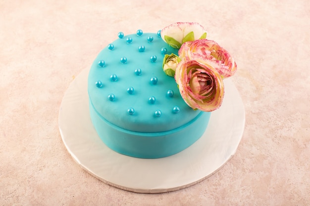 Una torta di compleanno blu di vista superiore con il fiore sulla parte superiore sul colore rosa della torta di compleanno della festa di celebrazione dello scrittorio