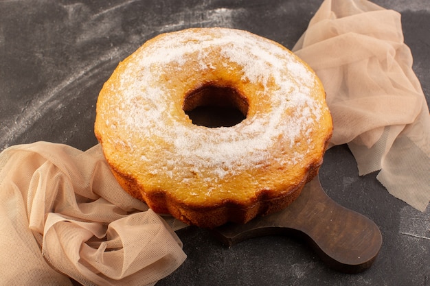 Una torta rotonda al forno vista dall'alto con zucchero in polvere sulla scrivania in legno