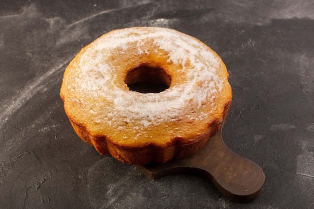 Una torta rotonda al forno vista dall'alto con zucchero in polvere sulla scrivania in legno