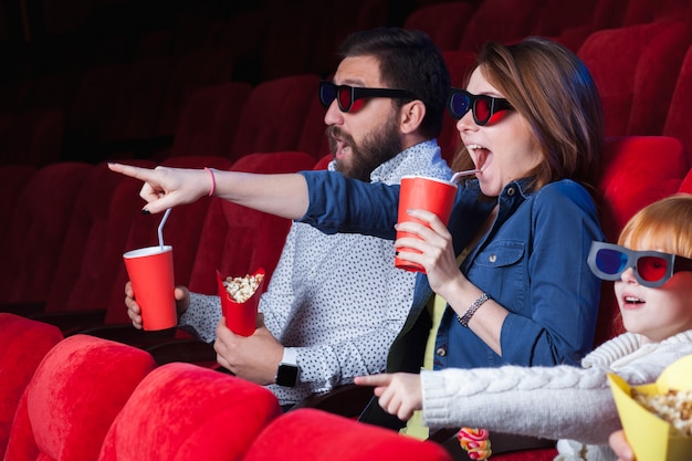 Una varietà di emozioni umane di amici che tengono una cola e popcorn al cinema.