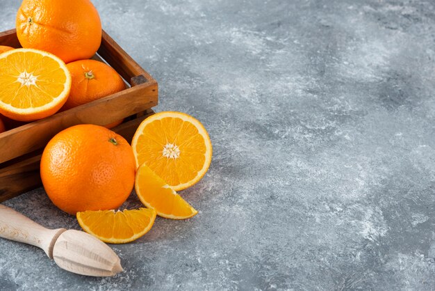 Una vecchia scatola di legno piena di succosa frutta arancione sul tavolo di pietra.