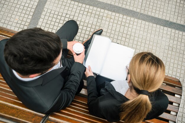 Una vista aerea dell&#39;uomo d&#39;affari e della donna di affari che si siedono sul documento della lettura del banco