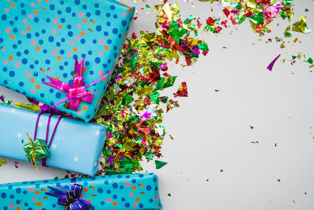 Una vista aerea di confezioni regalo avvolto con coriandoli colorati su sfondo grigio