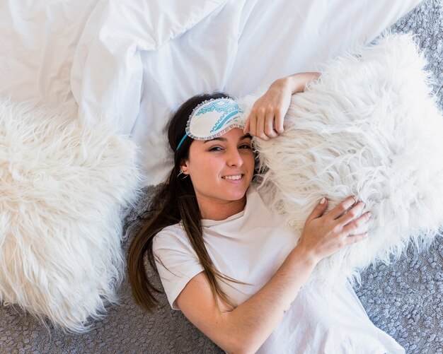 Una vista aerea di donna sdraiata sul letto con cuscini bianchi
