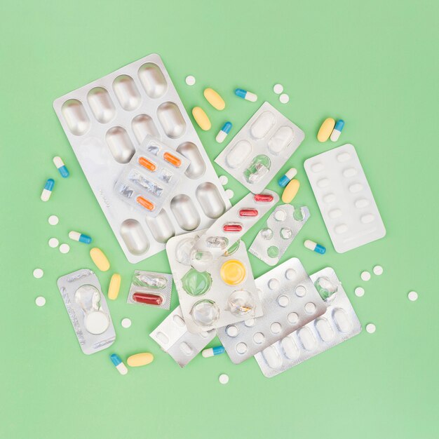 Una vista aerea di pillole e blister su sfondo verde
