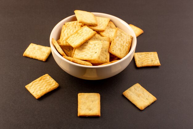 Una vista chiusa frontale salato patatine gustose crackers formaggio all'interno del piatto bianco sul buio