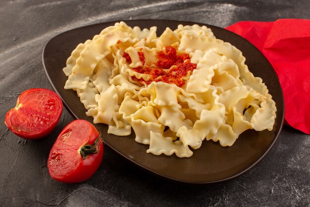 Una vista dall'alto cotta pasta italiana con salsa di pomodoro all'interno del piatto con pomodori freschi