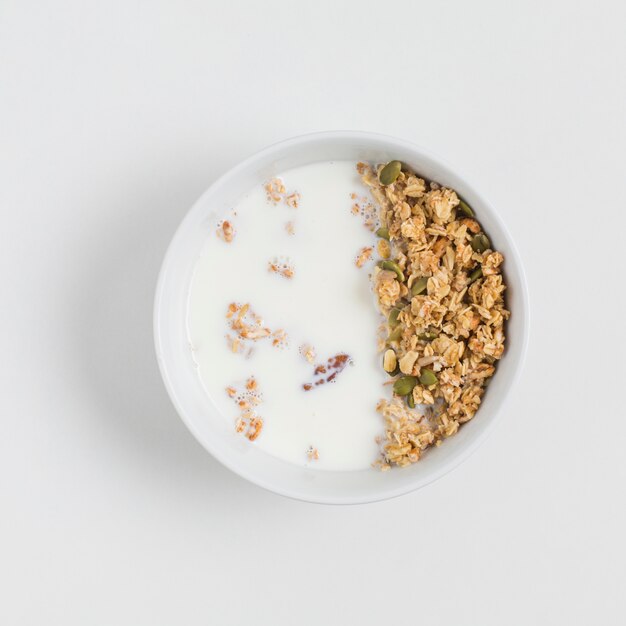 Una vista dall&#39;alto della ciotola con l&#39;avena; latte e semi di zucca su sfondo bianco