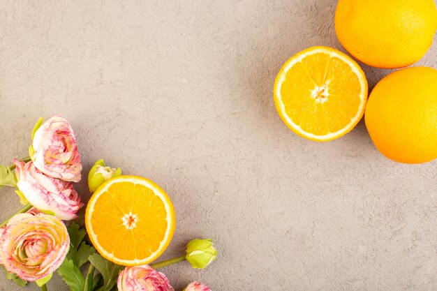 Una vista dall'alto di arance fresche acide mature affettate e tutto giallo agrume dolce vitamina tropicale giallo con fiori secchi sulla scrivania crema