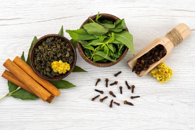 Una vista dall'alto di menta e cannella con spezie su bianco, foglie di ingredienti