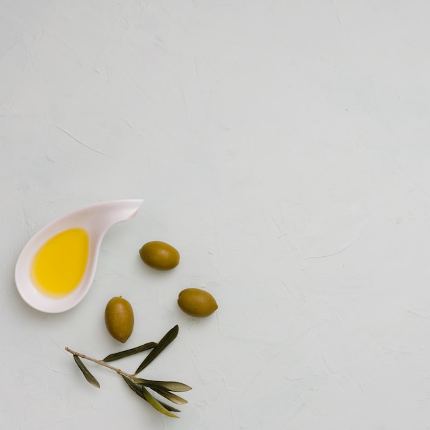 Una vista dall&#39;alto di oliva; foglie e olio su sfondo bianco di cemento