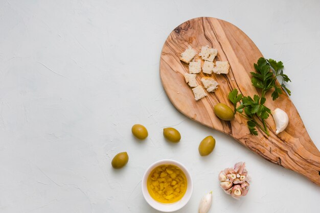 Una vista dall&#39;alto di pane; prezzemolo; aglio e ciotola di olio d&#39;oliva infuso isolato su sfondo bianco
